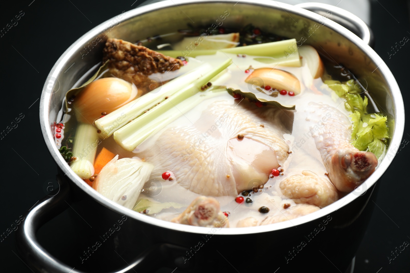 Photo of Whole raw turkey, cut onion, celery and spices in pot, closeup