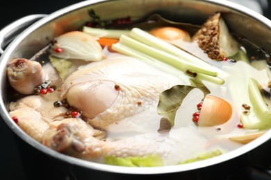 Photo of Whole raw turkey, cut onion, celery and spices in pot, closeup