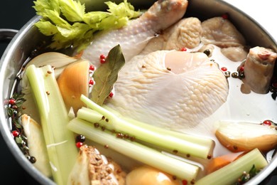 Photo of Whole raw turkey, cut onion, celery and spices in pot, closeup