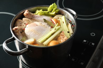 Photo of Whole fresh turkey, cut onion, celery and spices in pot on stove, closeup