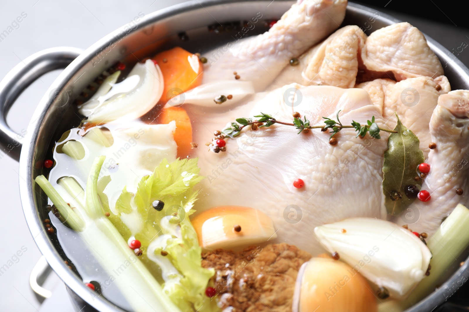 Photo of Whole fresh turkey, cut onion, carrot, celery and spices in pot, closeup