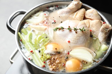 Photo of Whole fresh turkey, cut onion, celery and spices boiling in pot on table, closeup