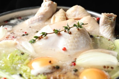 Photo of Whole fresh turkey, cut onion, thyme and spices boiling in pot, closeup