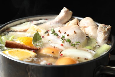 Photo of Whole fresh turkey, cut citrus fruits, onion, thyme and spices boiling in pot, closeup