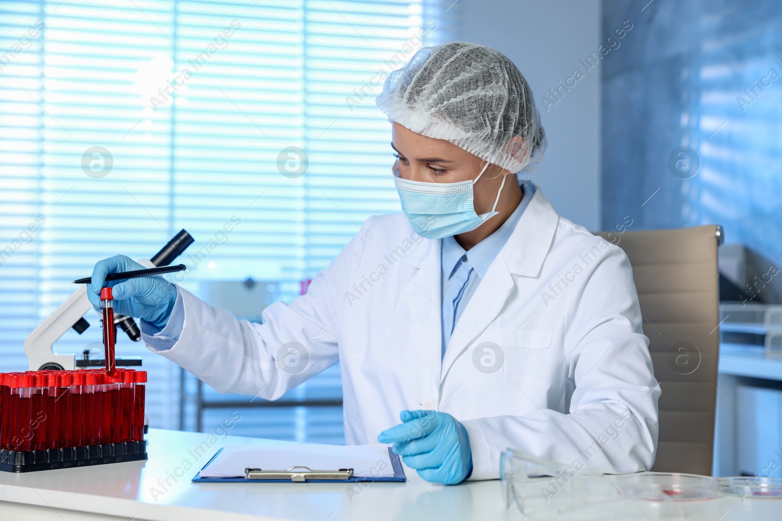 Photo of Laboratory testing. Doctor taking test tube with blood sample at table indoors