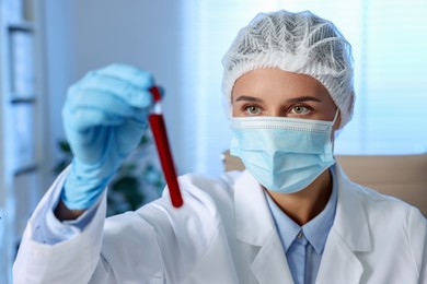 Laboratory testing. Doctor holding test tube with blood sample indoors