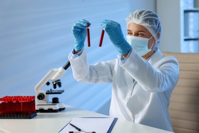 Laboratory testing. Doctor holding test tubes with blood samples at table indoors