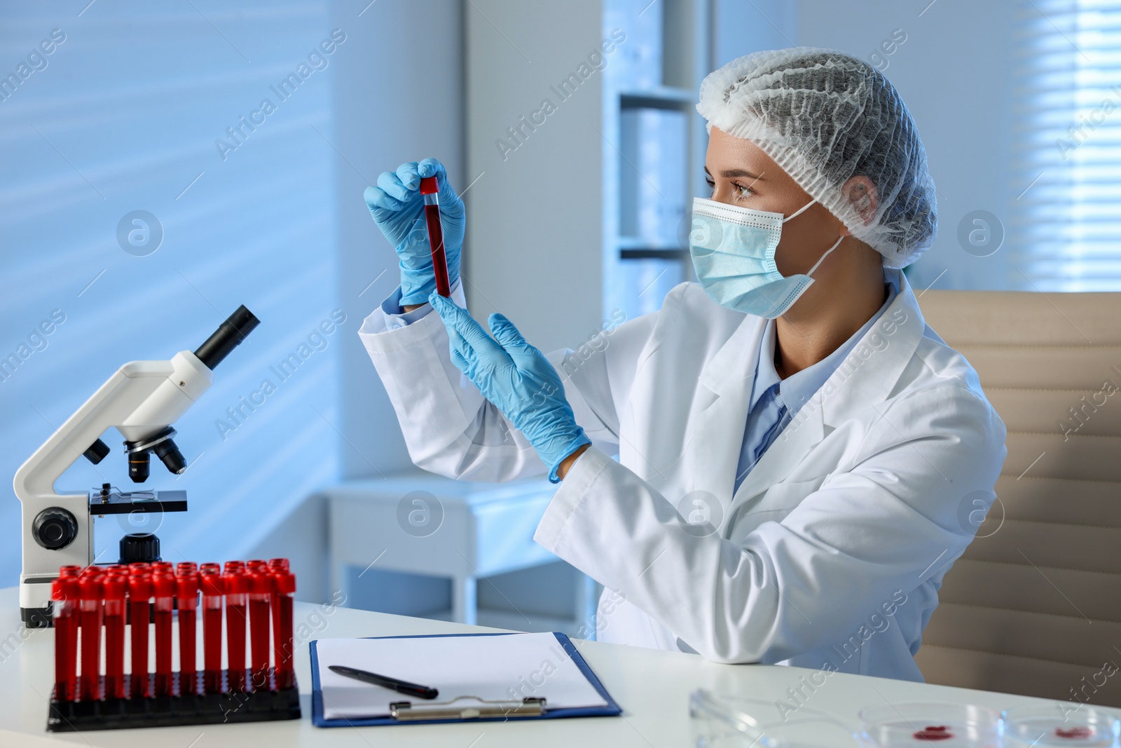 Photo of Laboratory testing. Doctor holding test tube with blood sample at table indoors