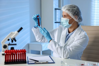 Photo of Laboratory testing. Doctor holding test tube with blood sample at table indoors