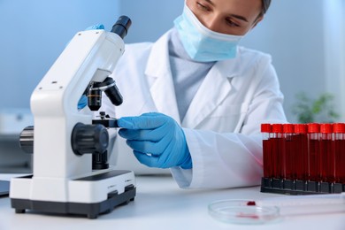 Photo of Laboratory testing. Doctor working with microscope at table indoors