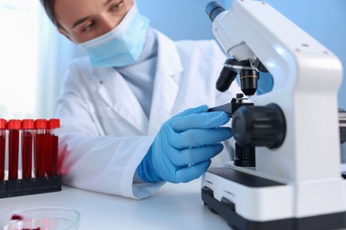 Photo of Laboratory testing. Doctor working with microscope at table indoors