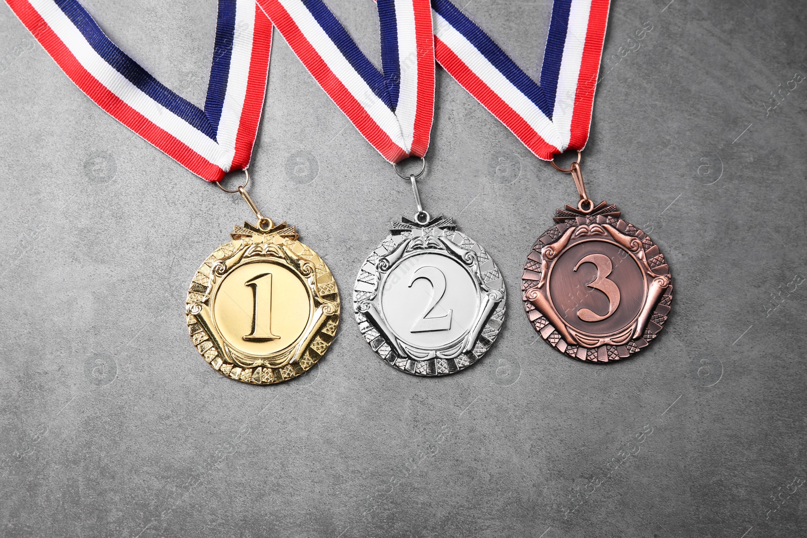 Photo of Golden, silver and bronze medals on grey background, top view