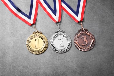 Photo of Golden, silver and bronze medals on grey background, top view