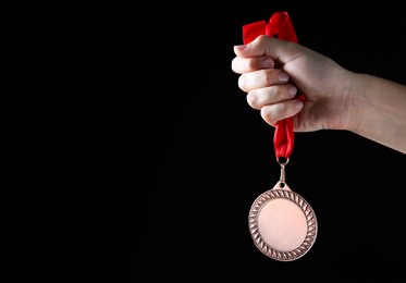 Photo of Woman with bronze medal on black background, closeup. Space for text