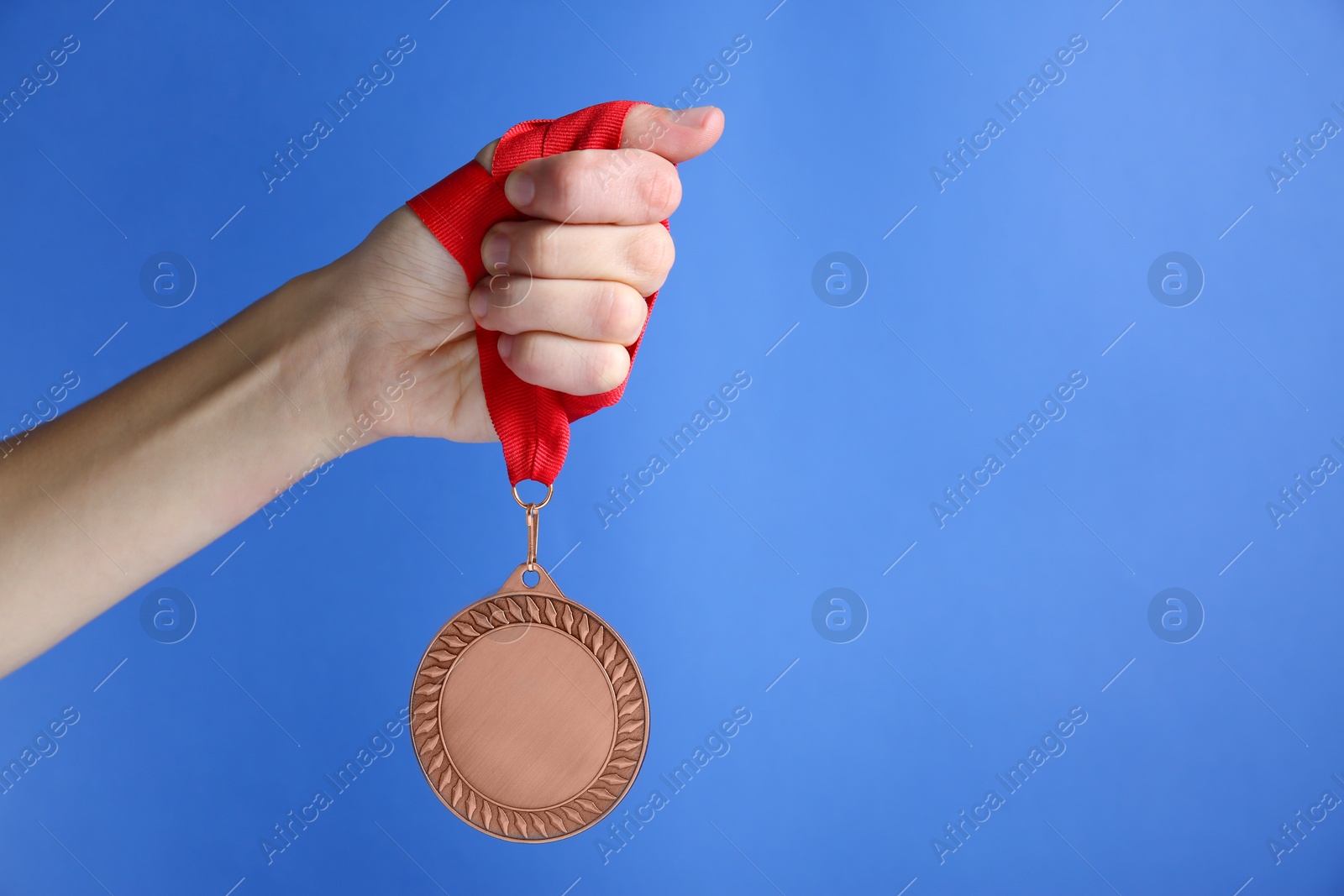 Photo of Woman with bronze medal on blue background, closeup. Space for text