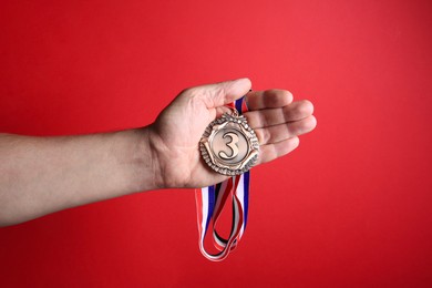 Photo of Man with bronze medal on red background, closeup