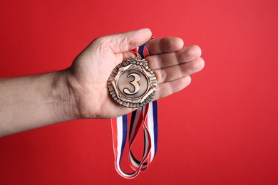 Photo of Man with bronze medal on red background, closeup