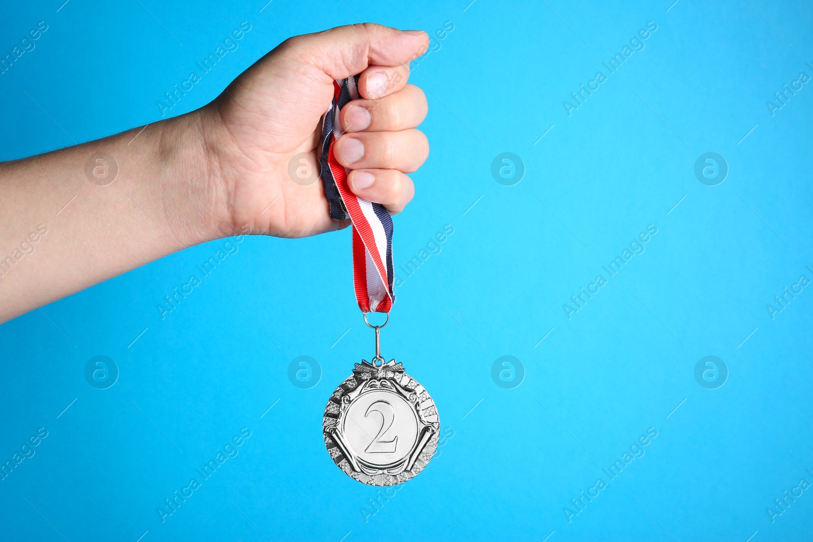 Photo of Man with silver medal on light blue background, closeup. Space for text