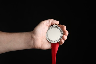 Photo of Man with silver medal on black background, closeup