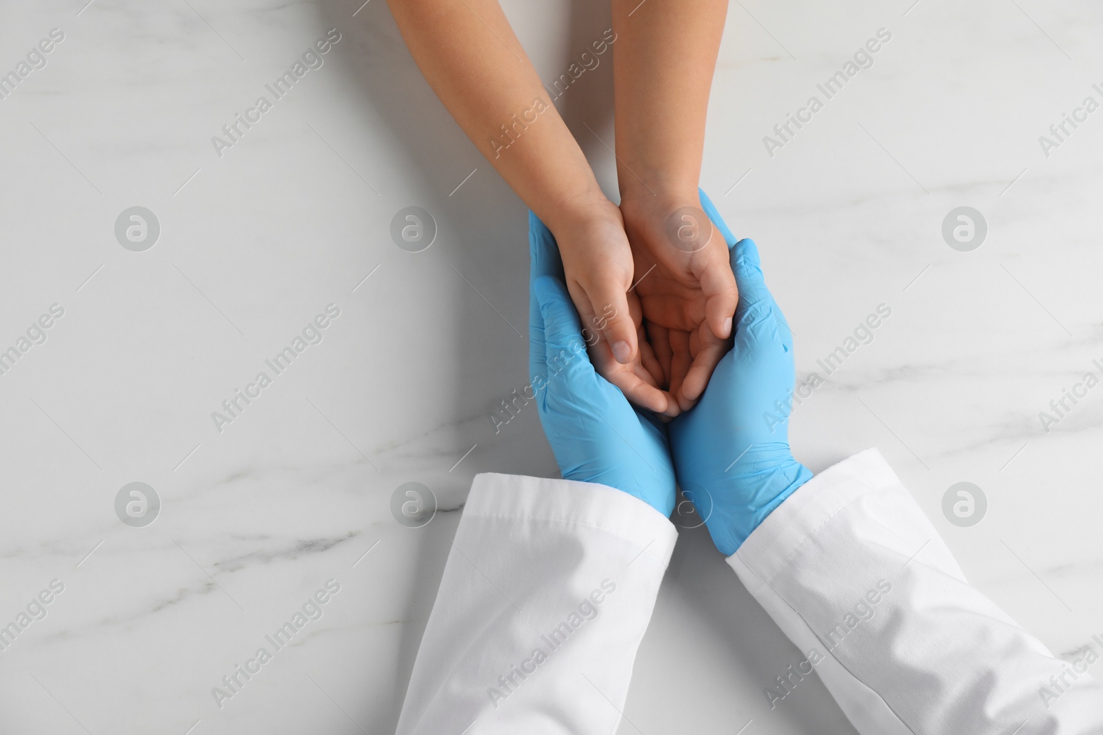 Photo of Doctor and child at white marble table, top view