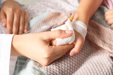 Photo of Doctor and child with intravenous drip at hospital, closeup