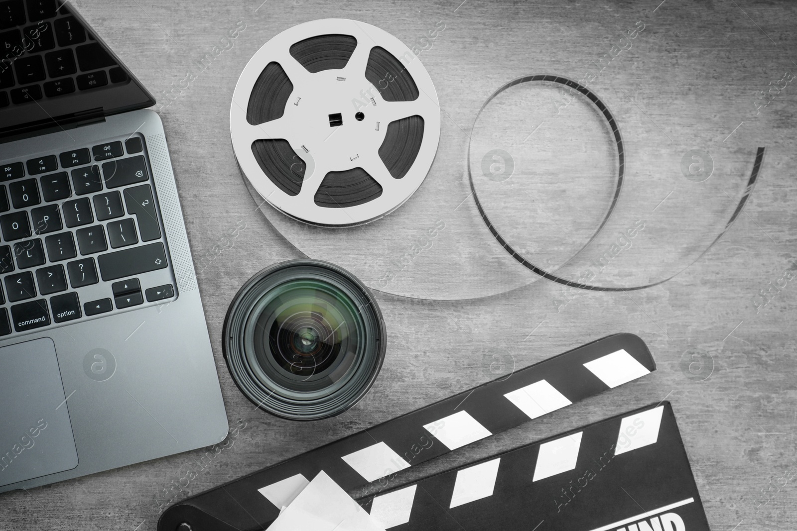 Photo of Flat lay composition with movie clapper, film reel and camera lens on grey textured table