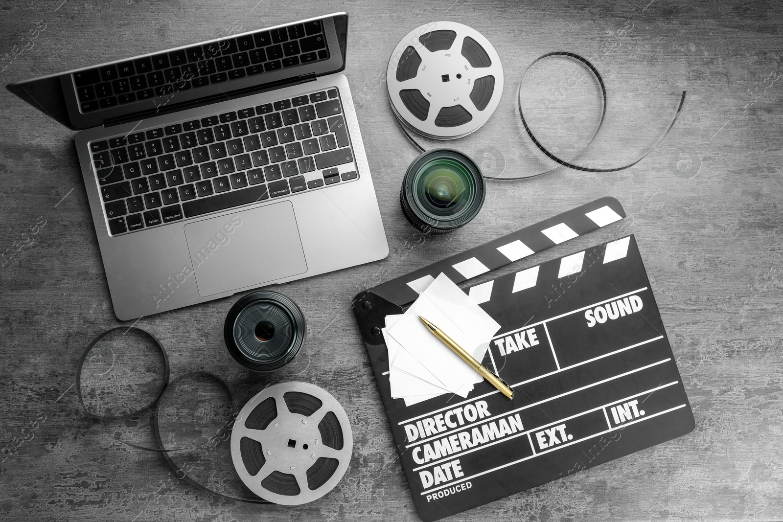 Photo of Flat lay composition with movie clapper, film reels and camera lens on grey textured table