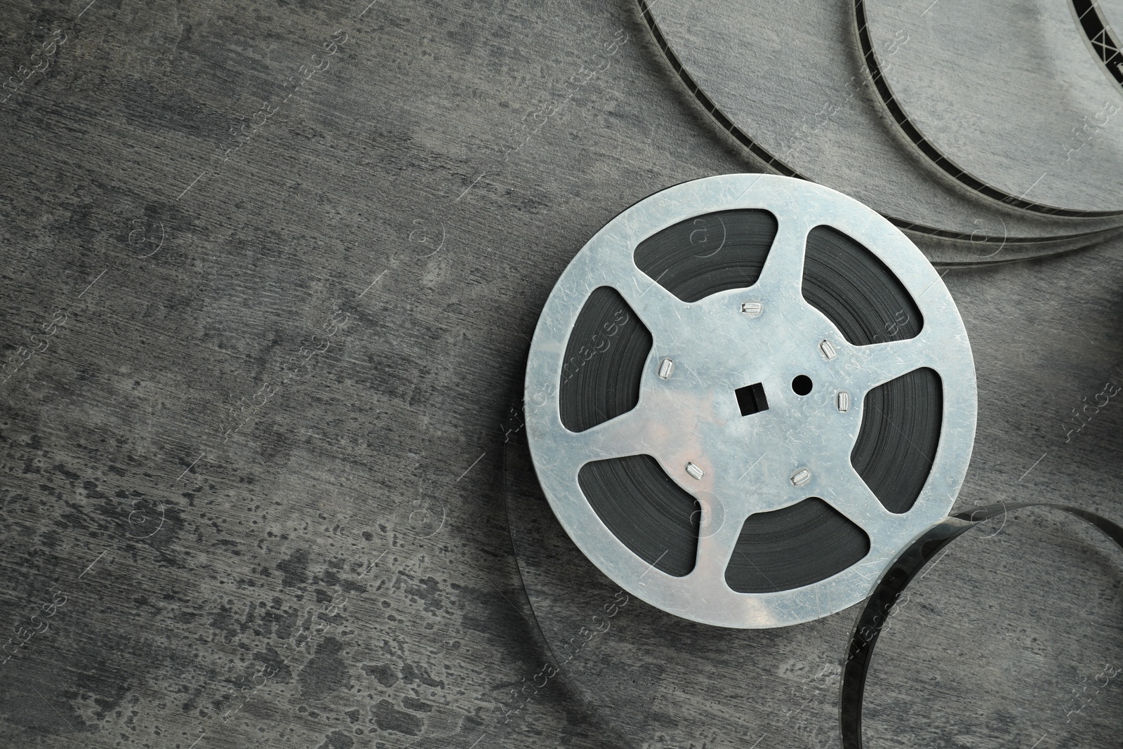 Photo of Film reel on grey textured table, top view. Space for text