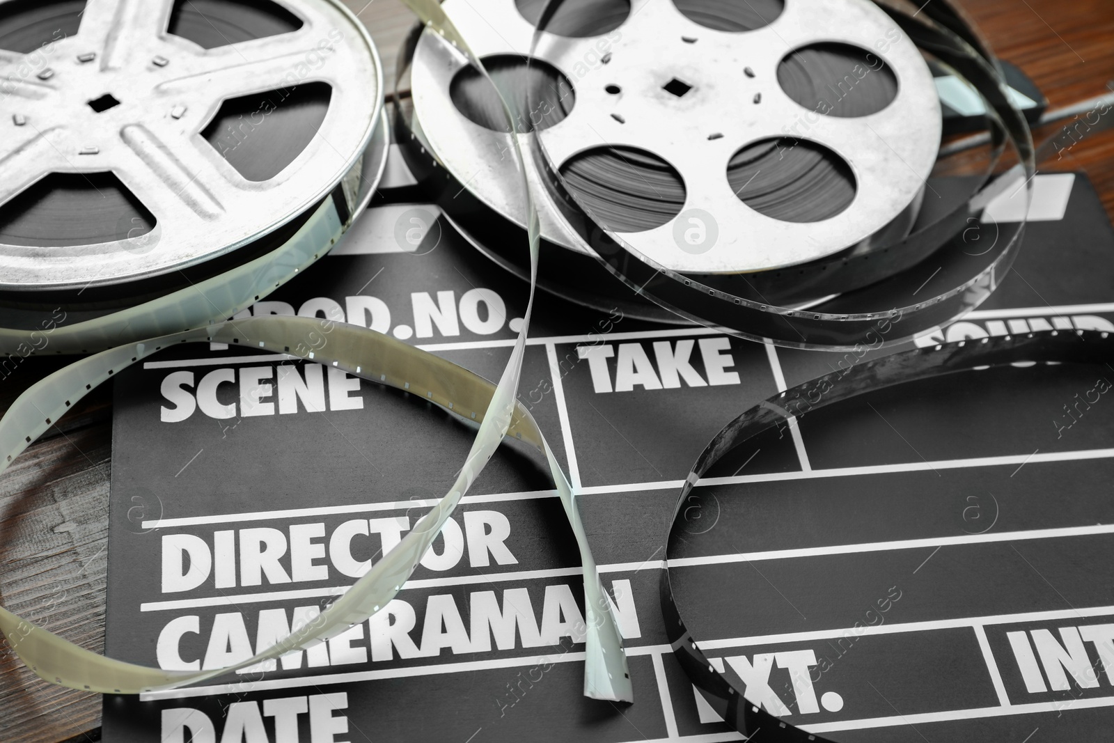 Photo of Movie clapper and film reels on wooden table, closeup