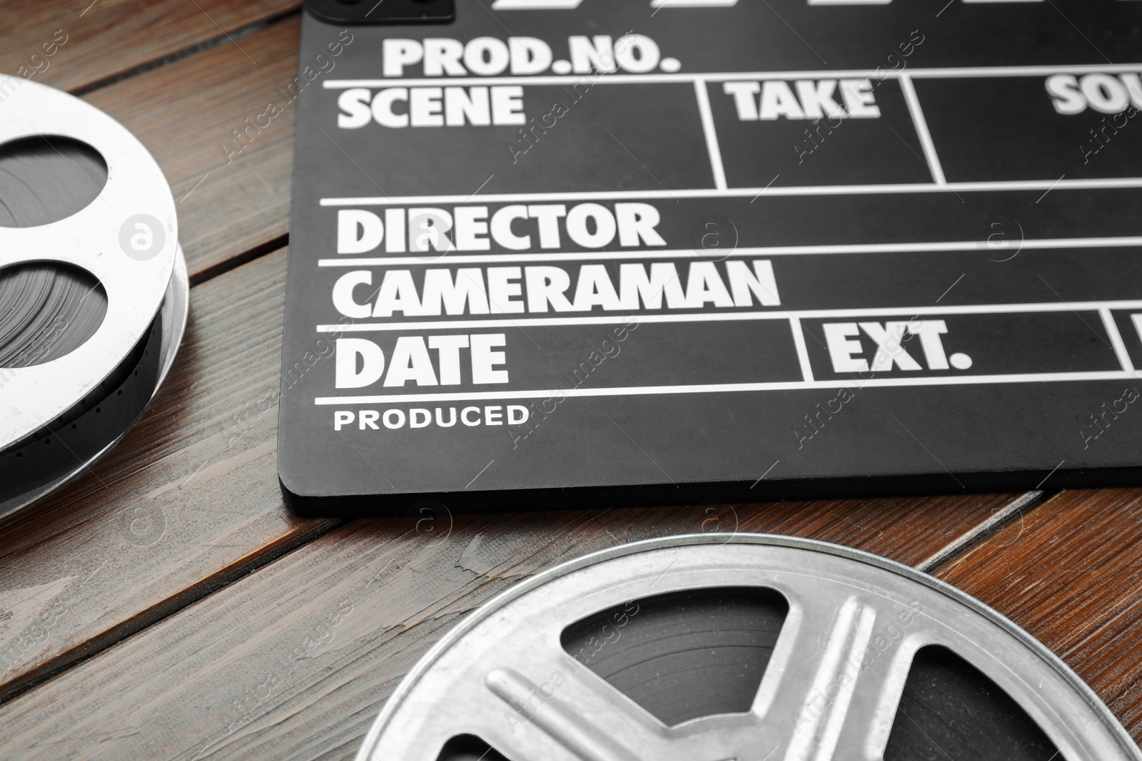 Photo of Movie clapper and film reels on wooden table, closeup