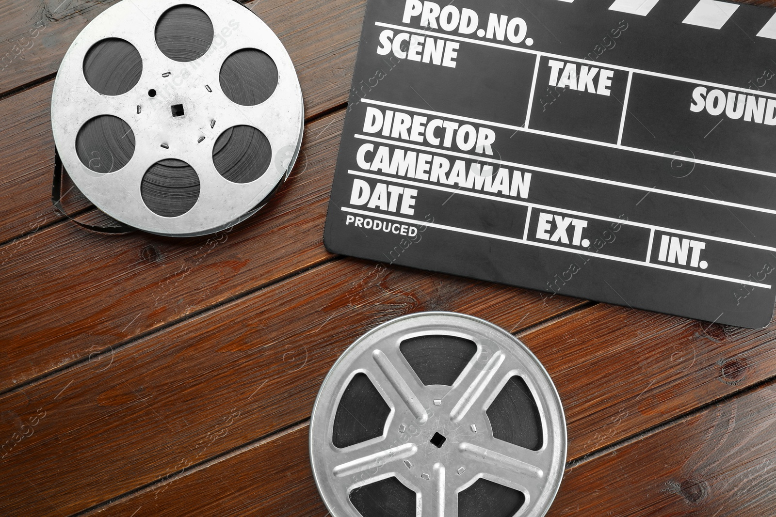 Photo of Movie clapper and film reels on wooden table, flat lay