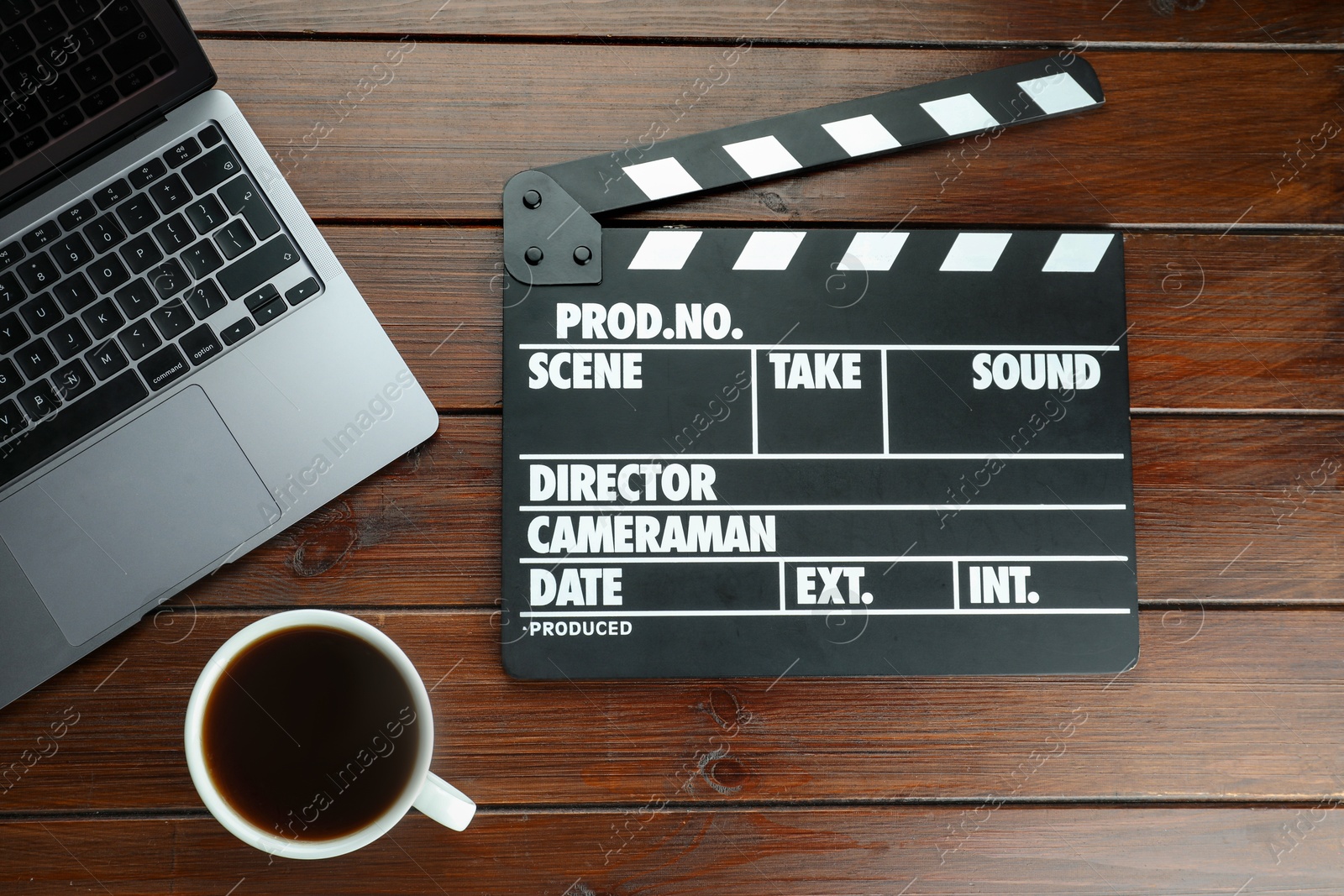 Photo of Movie clapper, laptop and coffee on wooden table, flat lay