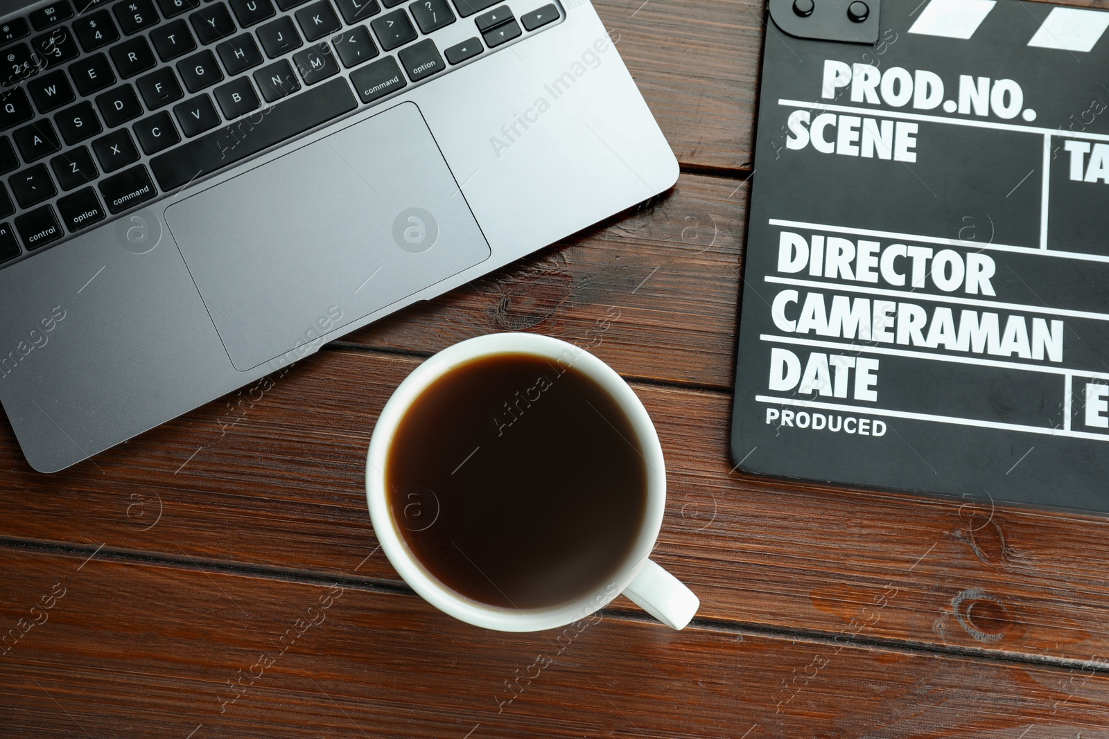 Photo of Movie clapper, laptop and coffee on wooden table, flat lay