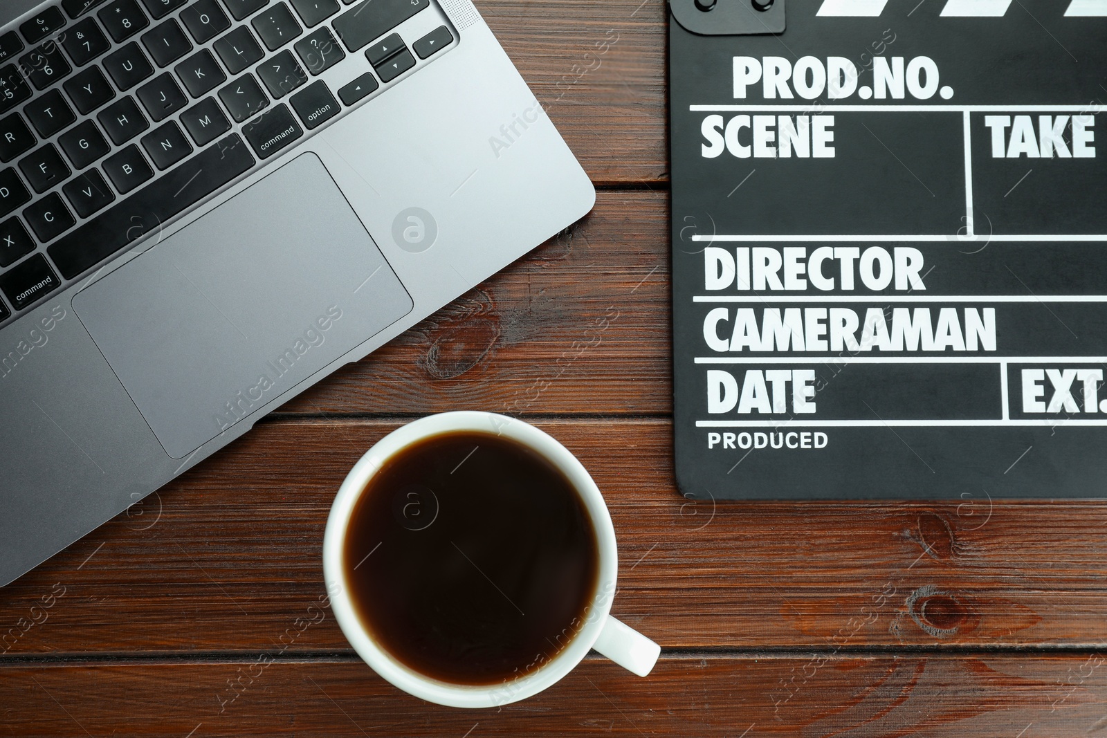 Photo of Movie clapper, laptop and coffee on wooden table, flat lay