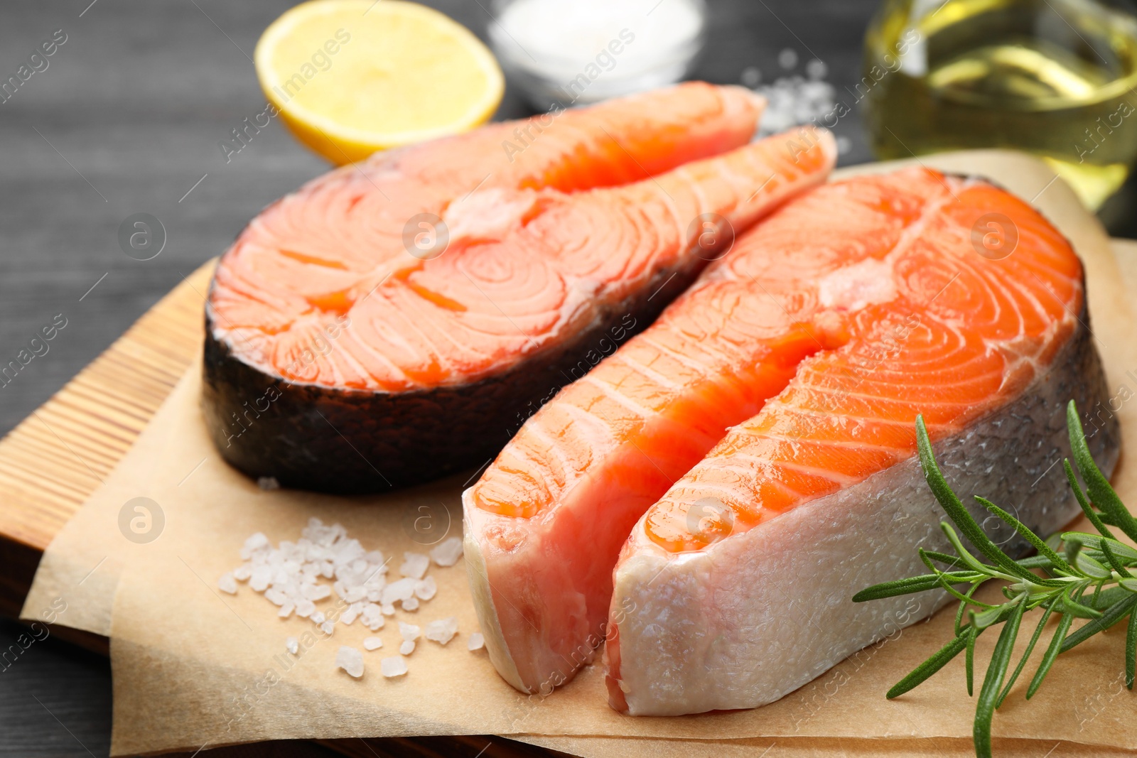 Photo of Fresh raw salmon steaks and spices on black table, closeup