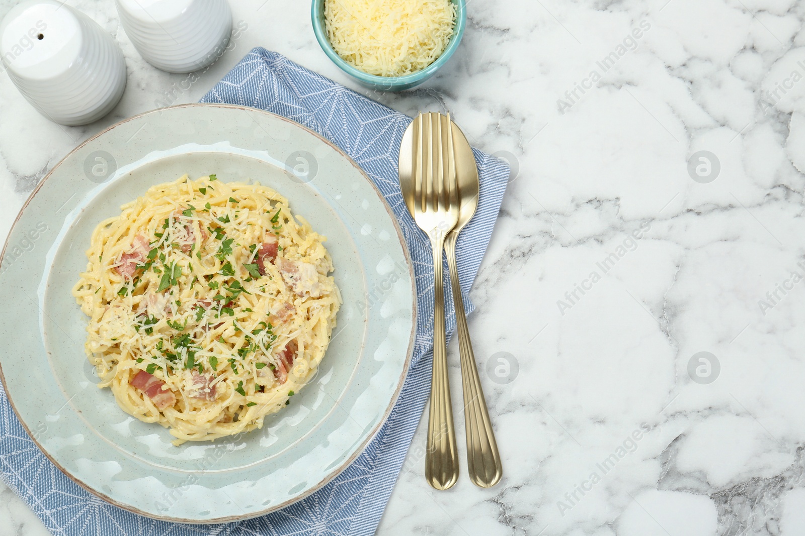 Photo of Delicious pasta Carbonara with bacon served on white marble table, flat lay. Space for text