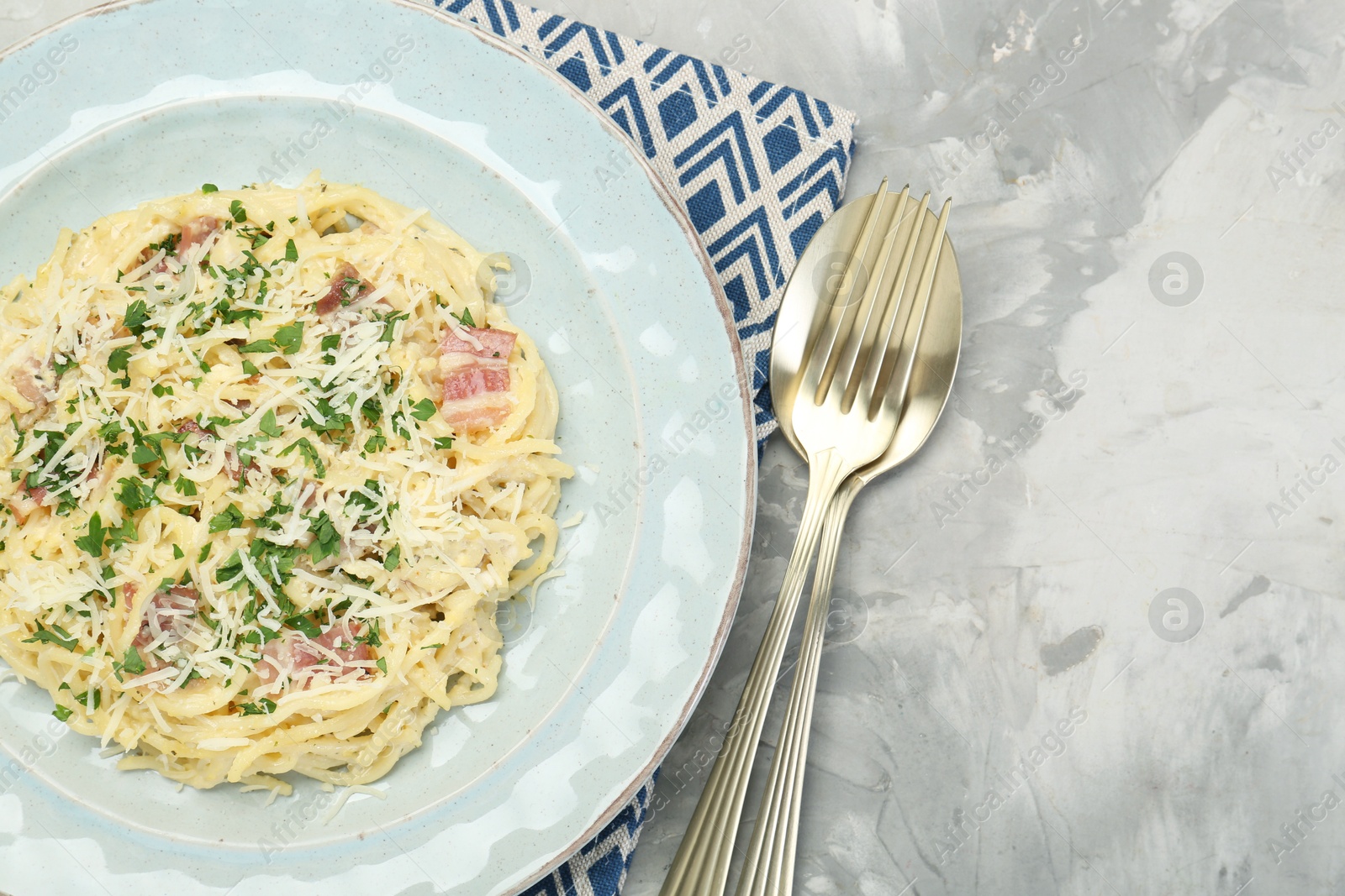 Photo of Delicious pasta Carbonara with bacon served on gray textured table, flat lay