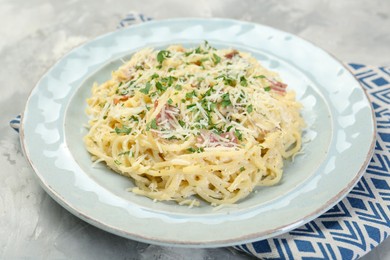 Photo of Delicious pasta Carbonara with bacon on gray textured table, closeup