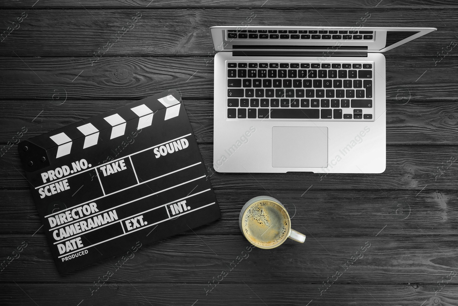 Photo of Movie clapper, laptop and cup of coffee on black wooden table, flat lay