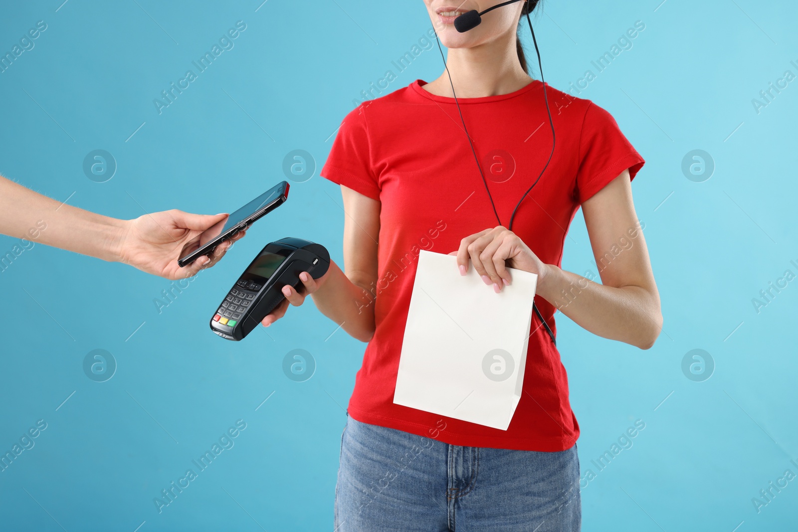 Photo of Fast-food worker taking payment from client via terminal on light blue background, closeup