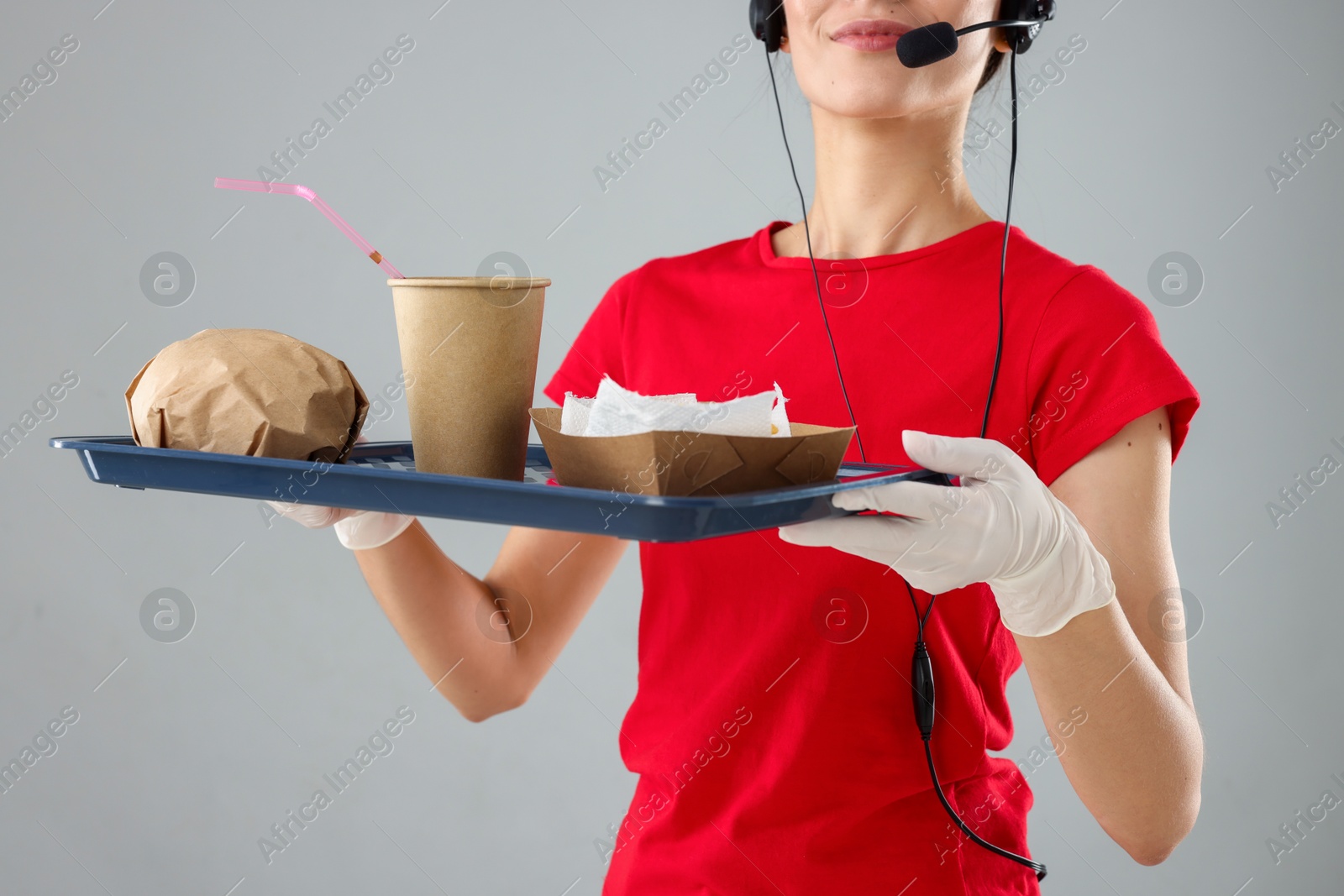 Photo of Fast-food worker holding tray with order on gray background, closeup