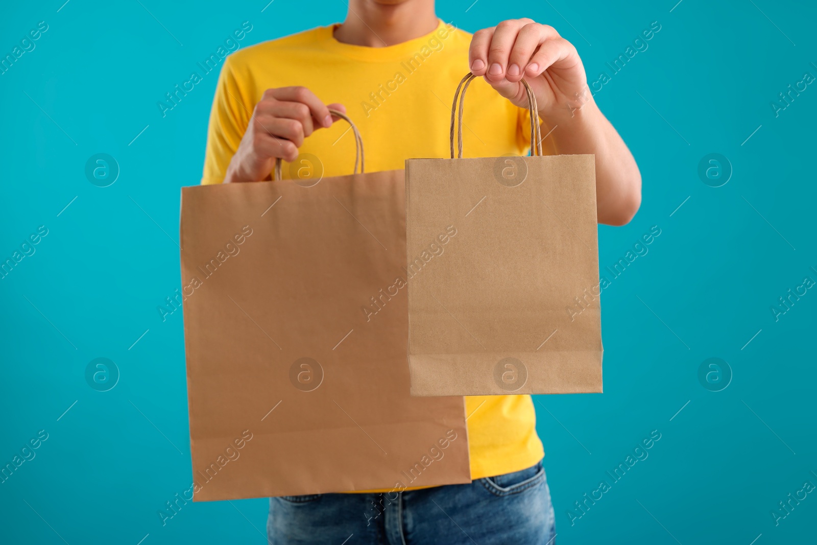 Photo of Fast-food worker with paper bags on light blue background, closeup