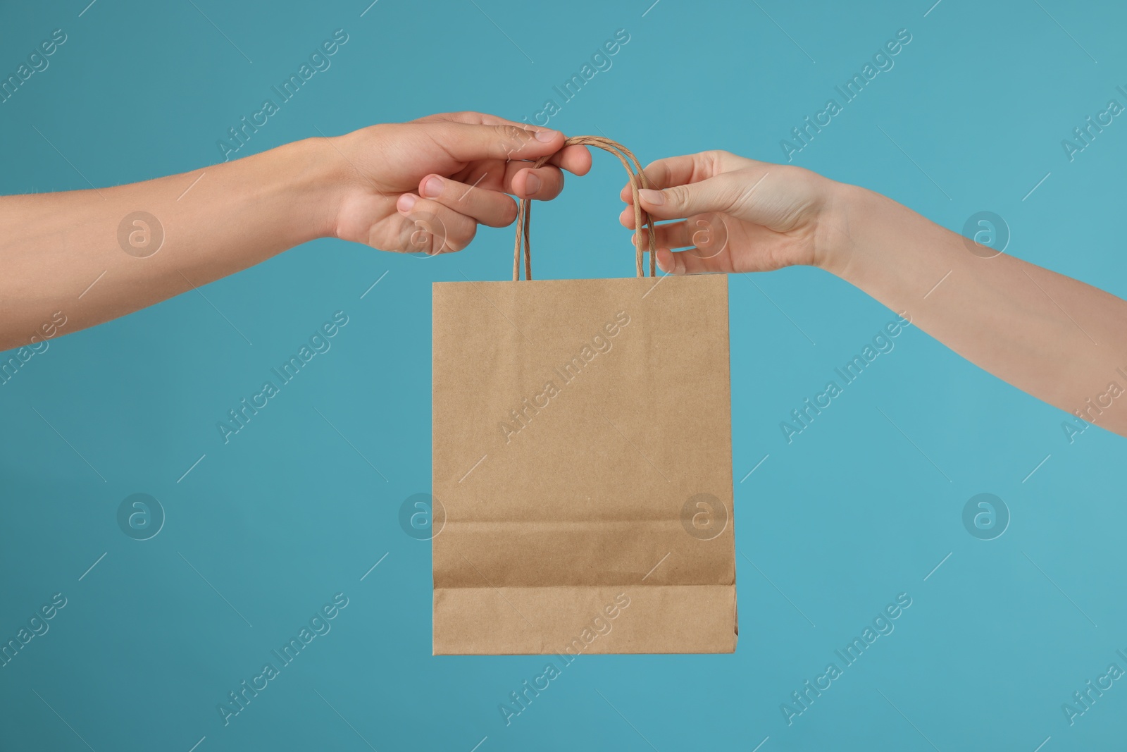 Photo of Fast-food worker giving customer's order on light blue background, closeup