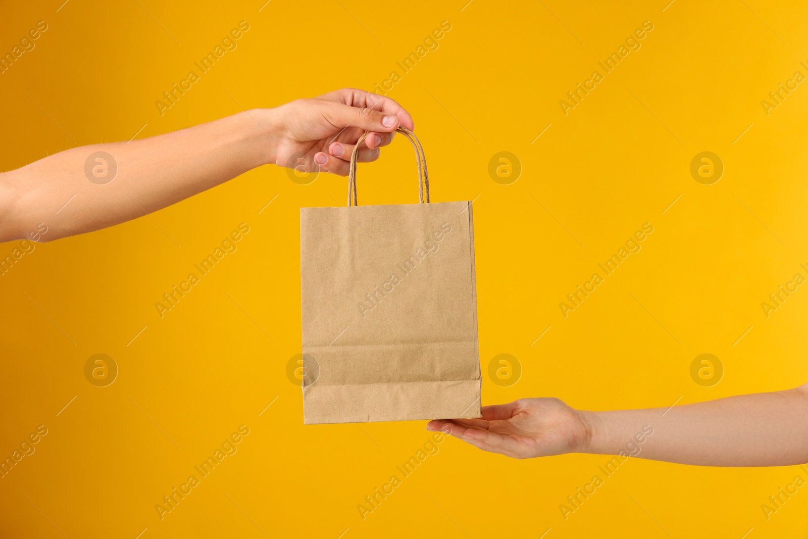 Photo of Fast-food worker giving customer's order on orange background, closeup