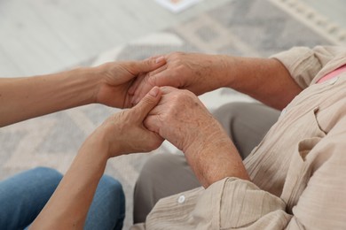 Photo of Caregiver supporting senior woman at home, closeup