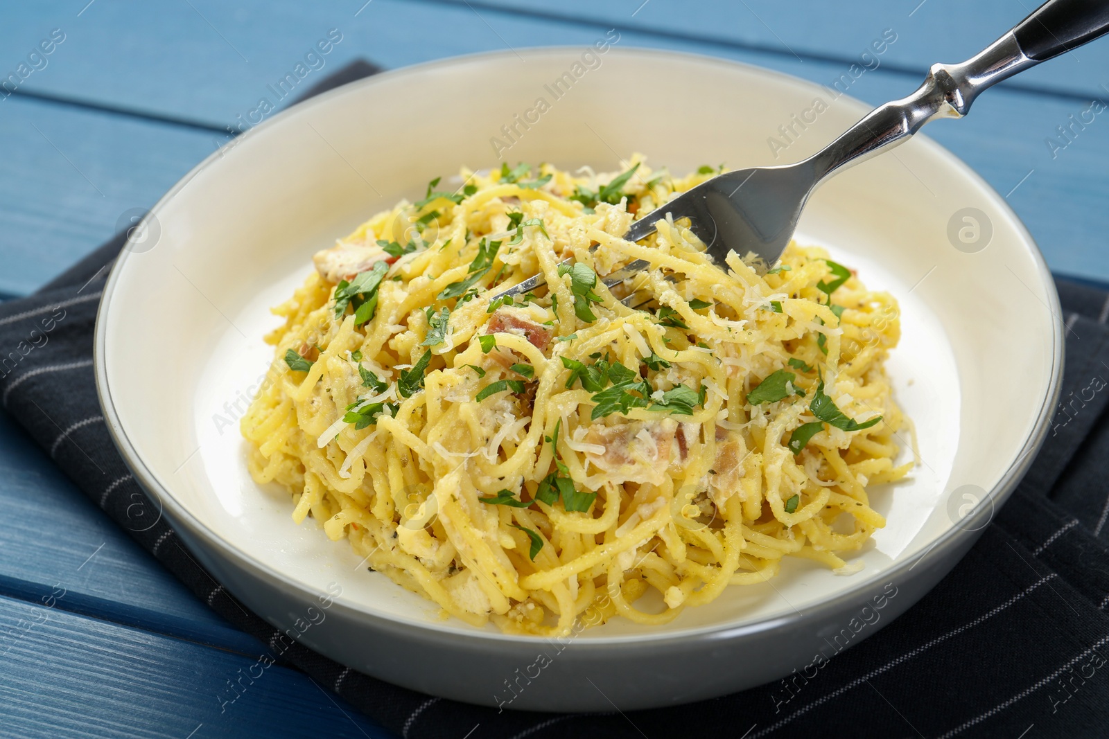 Photo of Delicious pasta Carbonara served on blue wooden table, closeup