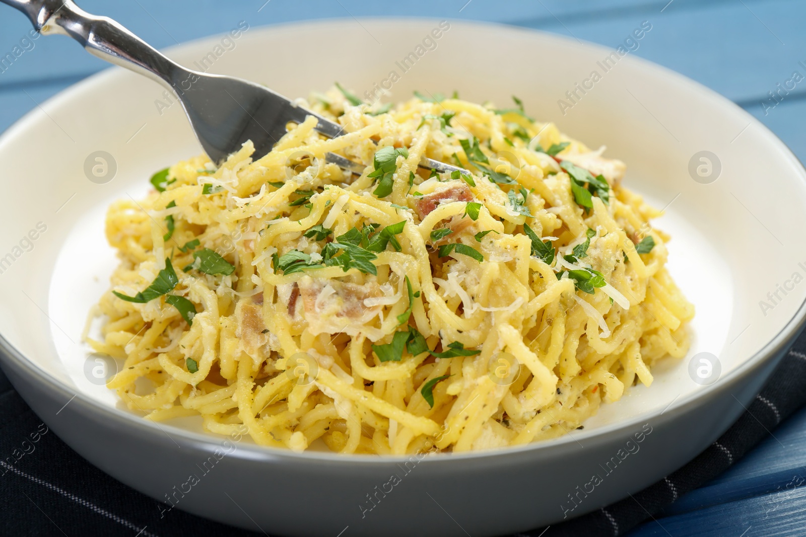 Photo of Delicious pasta Carbonara served on blue table, closeup