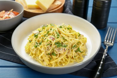 Photo of Delicious pasta Carbonara served on blue wooden table, closeup