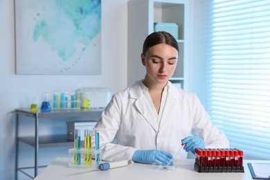 Photo of Laboratory testing. Doctor dripping blood sample into Petri dish at table indoors