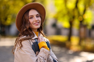 Photo of Charming young woman in stylish outfit on city street, space for text. Autumn season